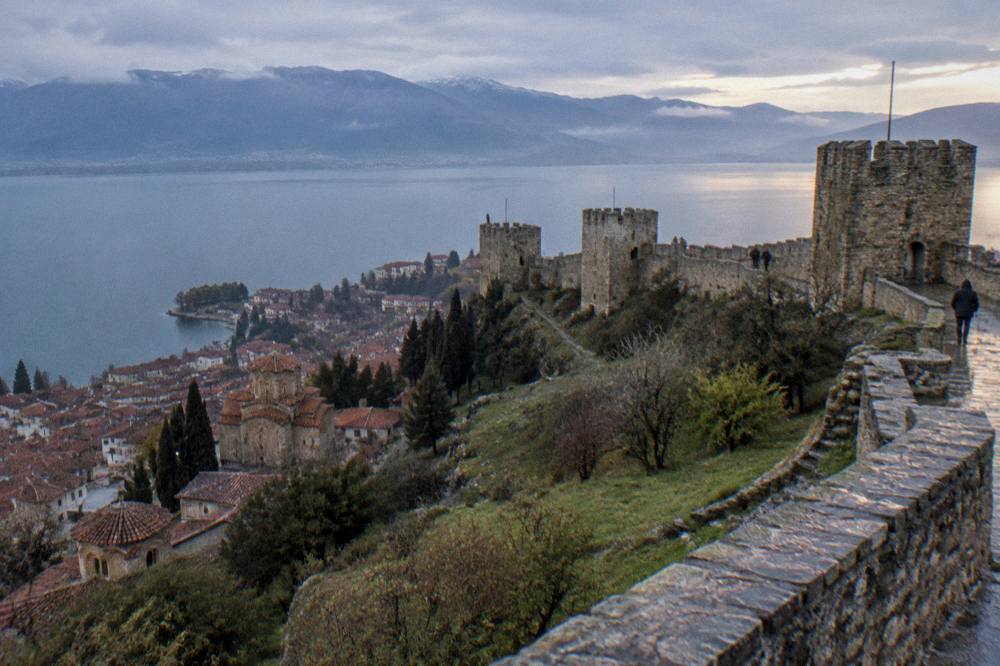 Evening light over a lake town with church domes and a fortress wall