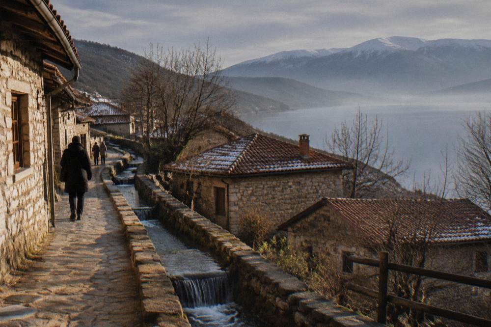 Wooded mountain slopes above a village under a winter sky