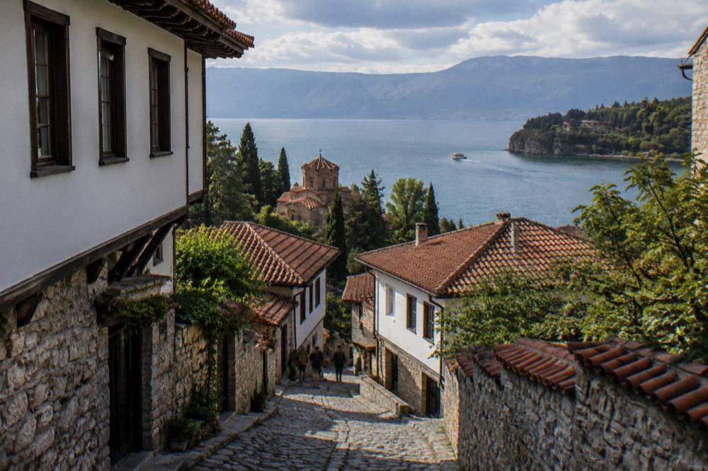 A small boat crossing Lake Ohrid toward the wooded headland near St Naum