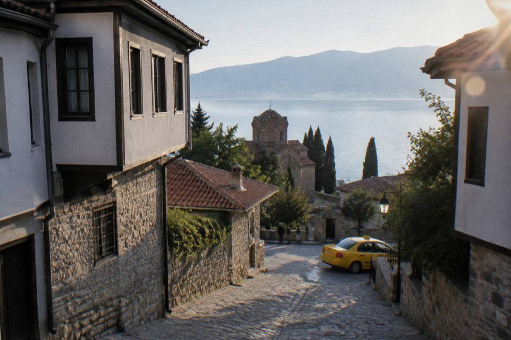 A taxi waiting on a street corner in Ohrid with the lake behind