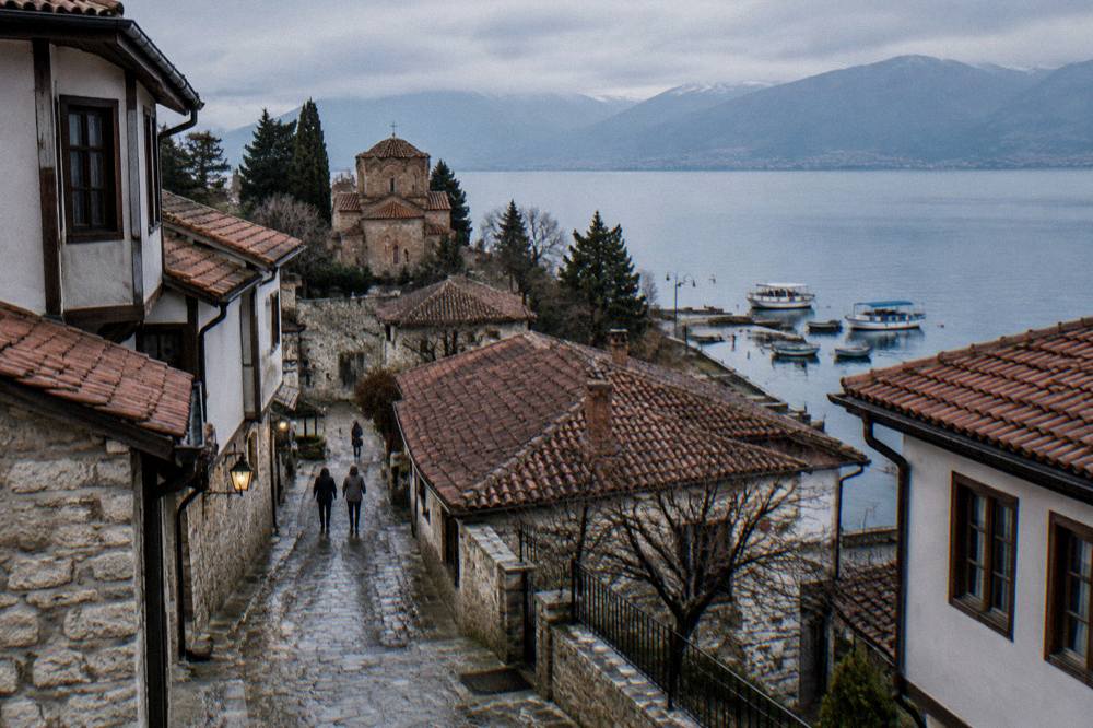The Ohrid lakeshore promenade at dusk with boats moored at the port