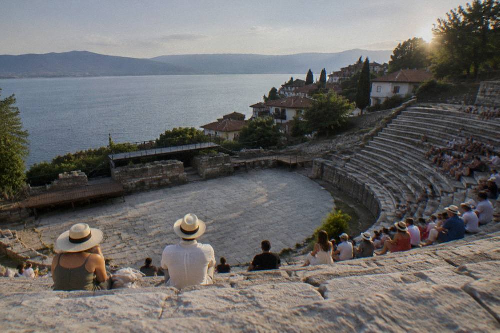 Audience seated in the stone rows of the Ancient Theatre of Ohrid at dusk