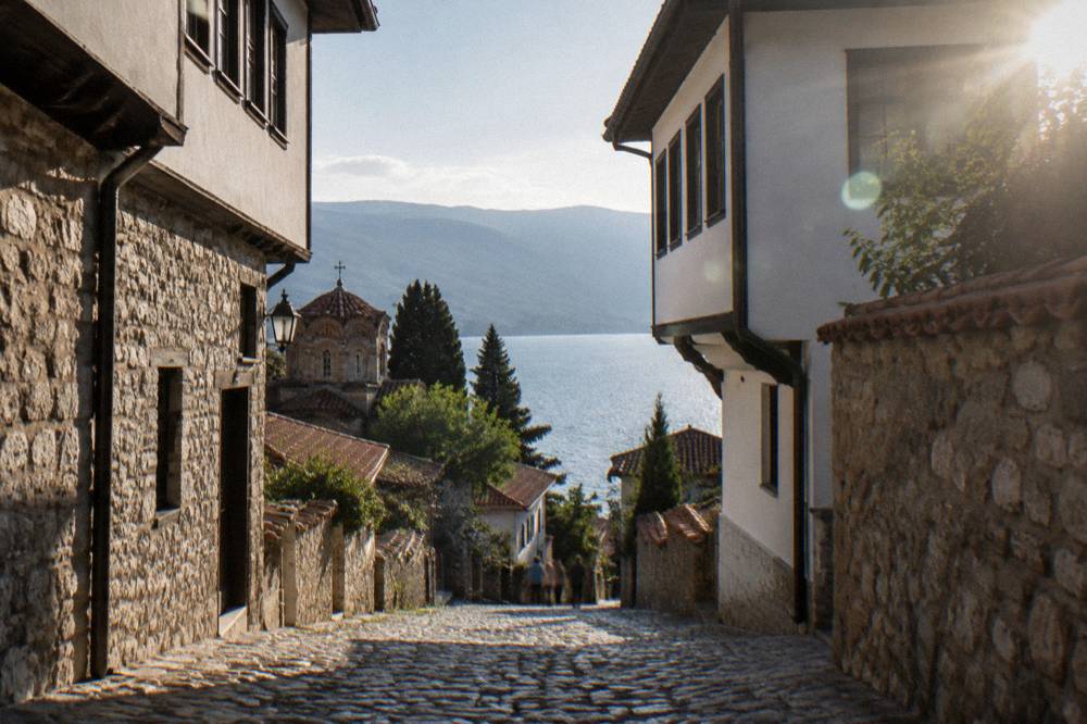 A winding mountain road descending toward the blue water of Lake Ohrid