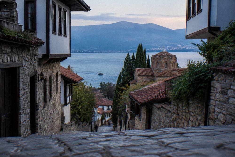 A boat on calm blue water near the Ohrid lakeshore in late afternoon light
