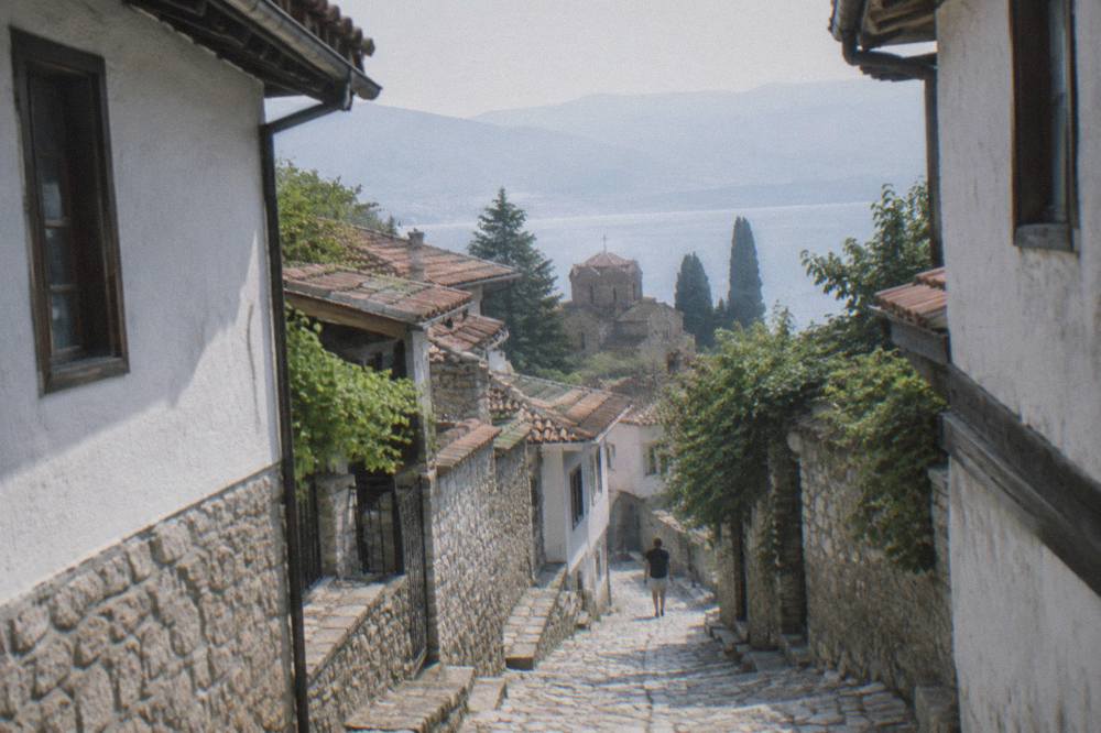 A narrow stone lane in Ohrid old town with whitewashed walls and worn steps