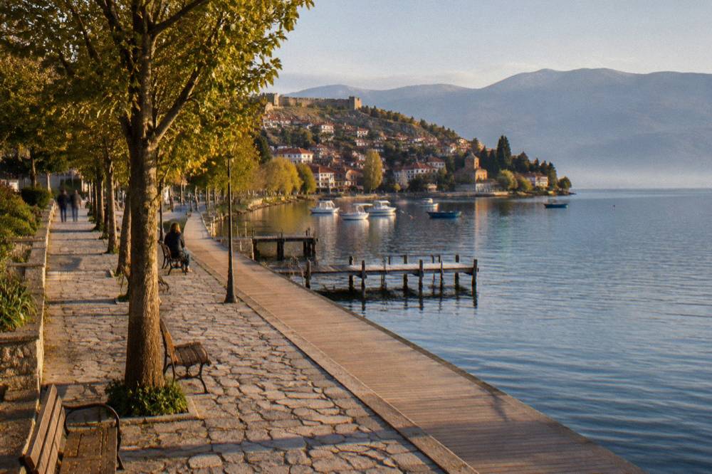 The lakeside boardwalk in Ohrid with a calm lake and moored boats in the distance