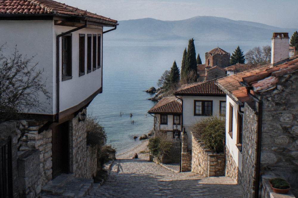 Swimmers in clear green water near a pebble beach on Lake Ohrid
