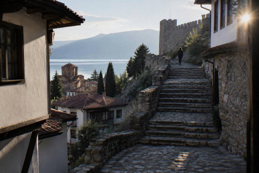 Wide stone steps rising between old houses toward a fortress wall in Ohrid