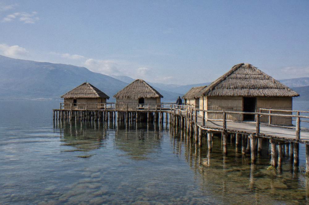 Reconstructed thatched pile dwellings standing over the shallows at Bay of Bones