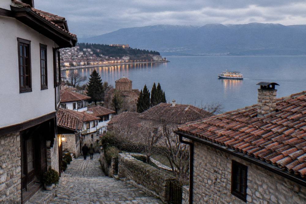 An evening cruise boat on calm water with Ohrid's harbour lights along the shore