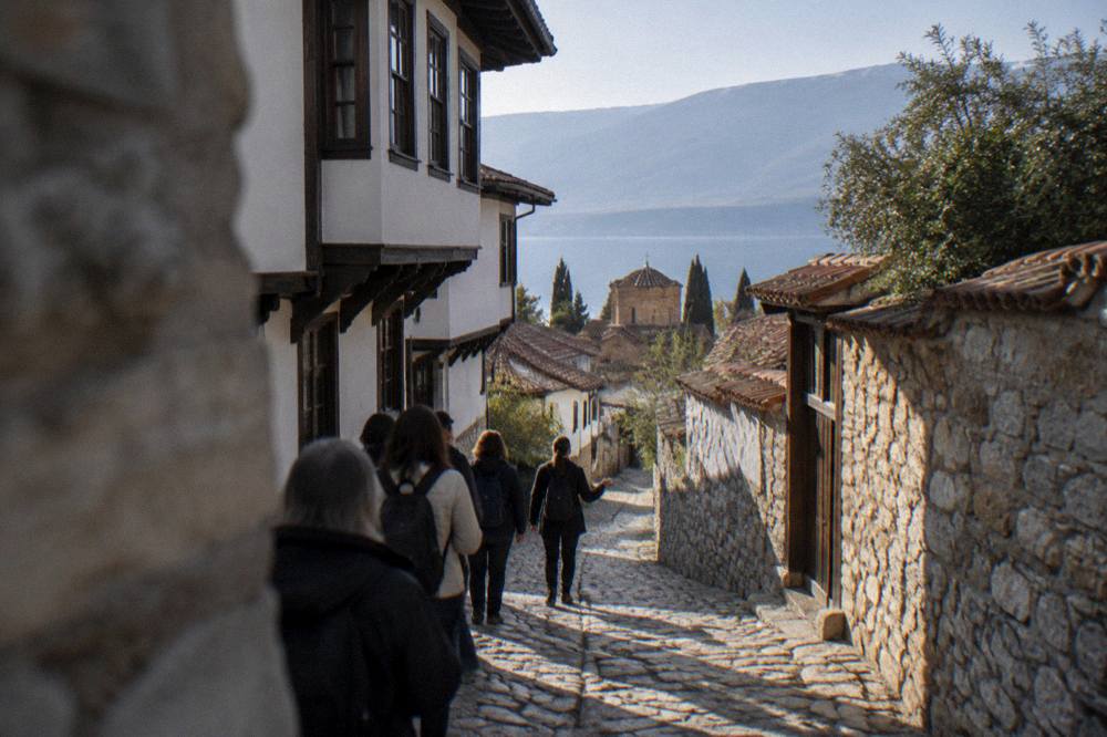 Group of visitors walking with a guide through narrow stone lanes of an old lakeside town