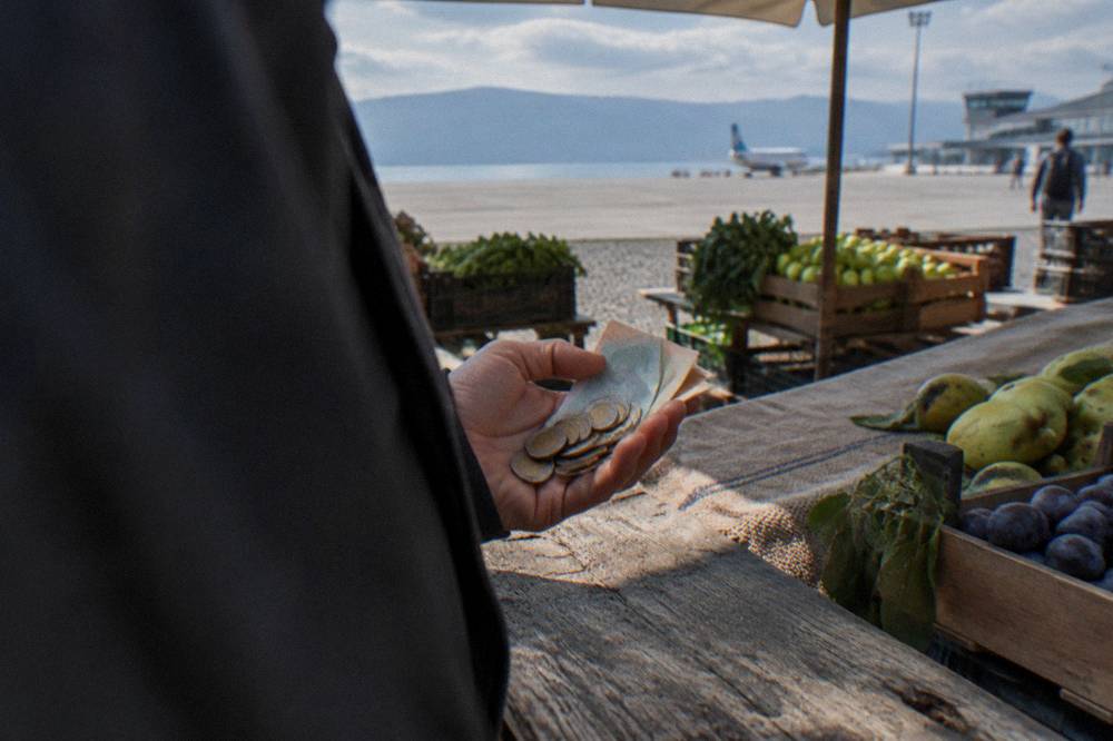Macedonian denar banknotes and coins held in a hand over a market stall