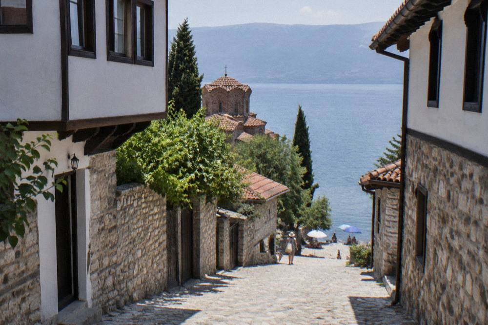 Families with umbrellas on a pebble beach beside Lake Ohrid on a summer day