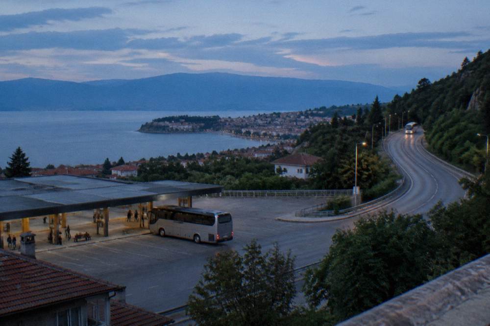 A highway winding through green Balkan hills with a coach in the distance