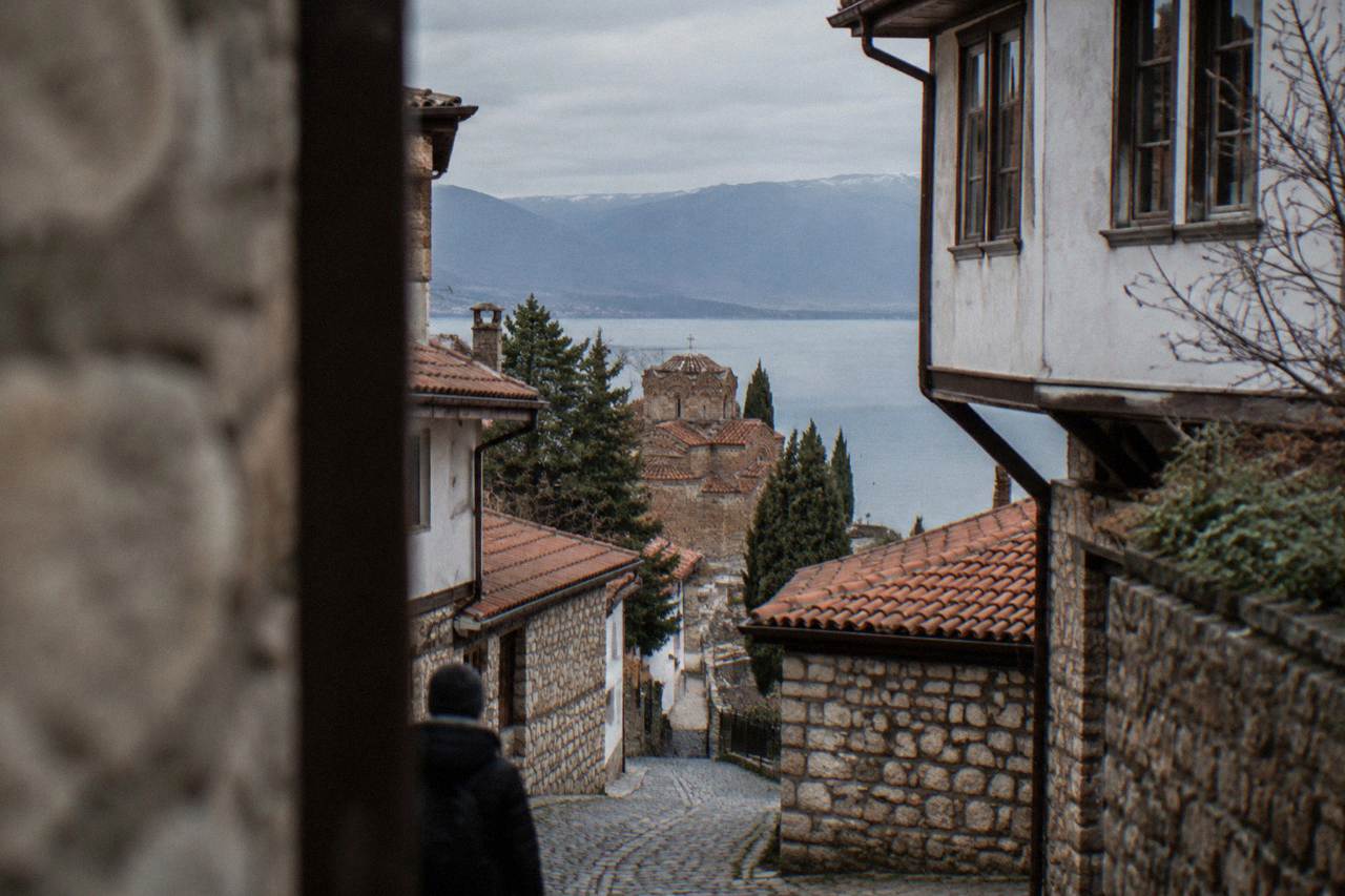 A quiet road winding along the shore of Lake Ohrid toward wooded hills