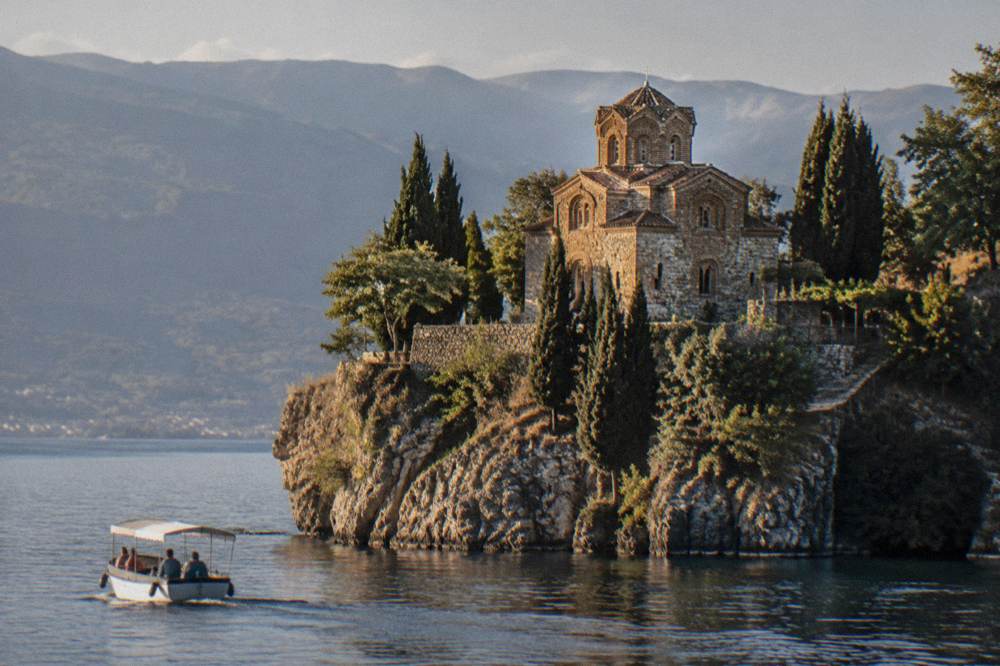 Cliffside church seen from the water with a small boat passing below