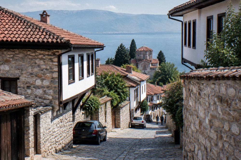A narrow stone lane in Ohrid old town with parked cars and old stone walls