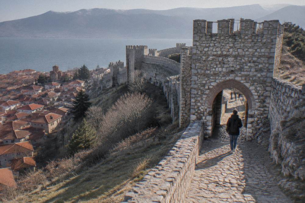 Walker passing through a stone gate in the fortress walls above Ohrid