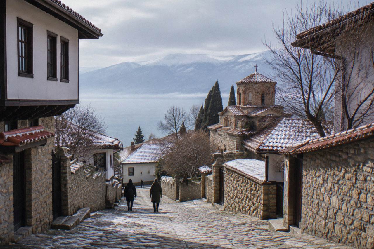 Stone lanes of Ohrid old town under a light winter frost, with the lake and mountains beyond