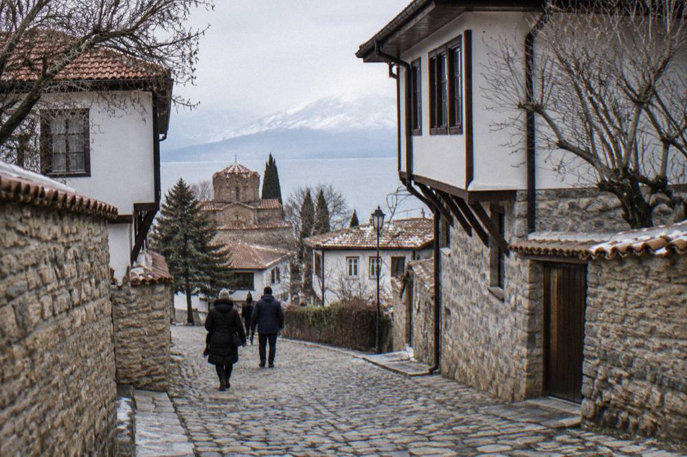 A quiet cobbled street in Ohrid old town in winter with stone walls and bare trees