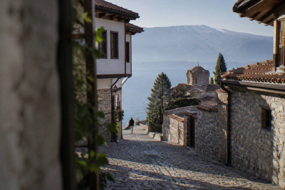 A lakefront promenade in Ohrid with signage and moored small boats along the shore