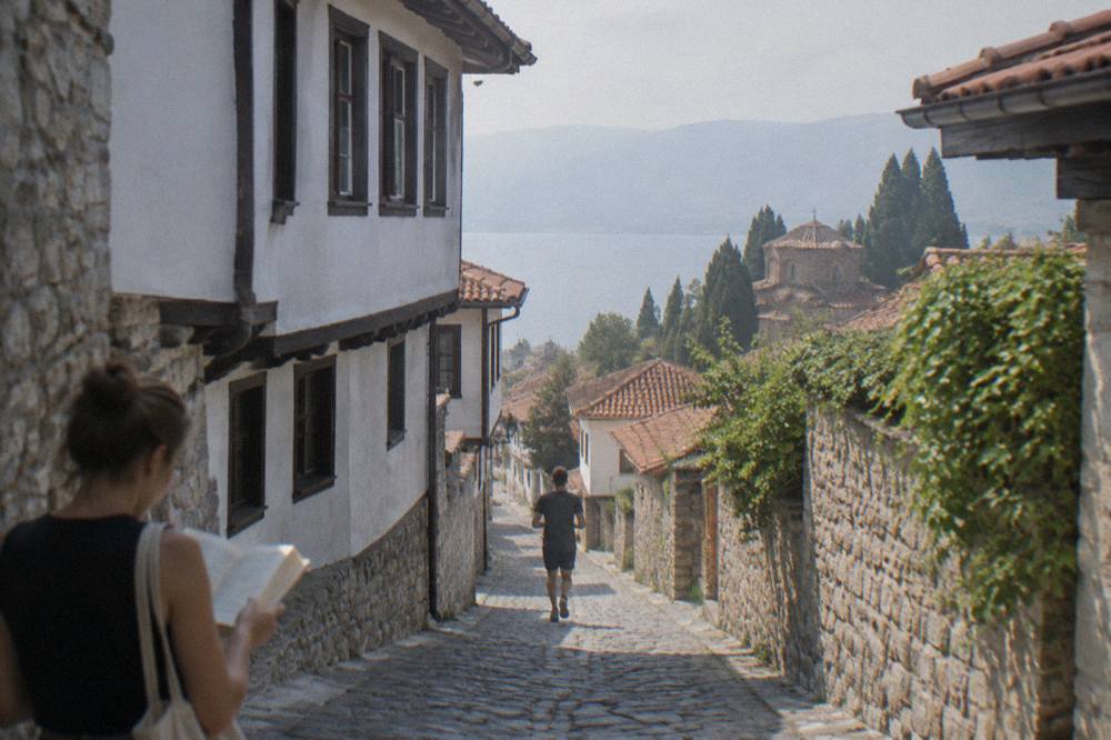 A visitor reading a bilingual information sign beside an old church in Ohrid