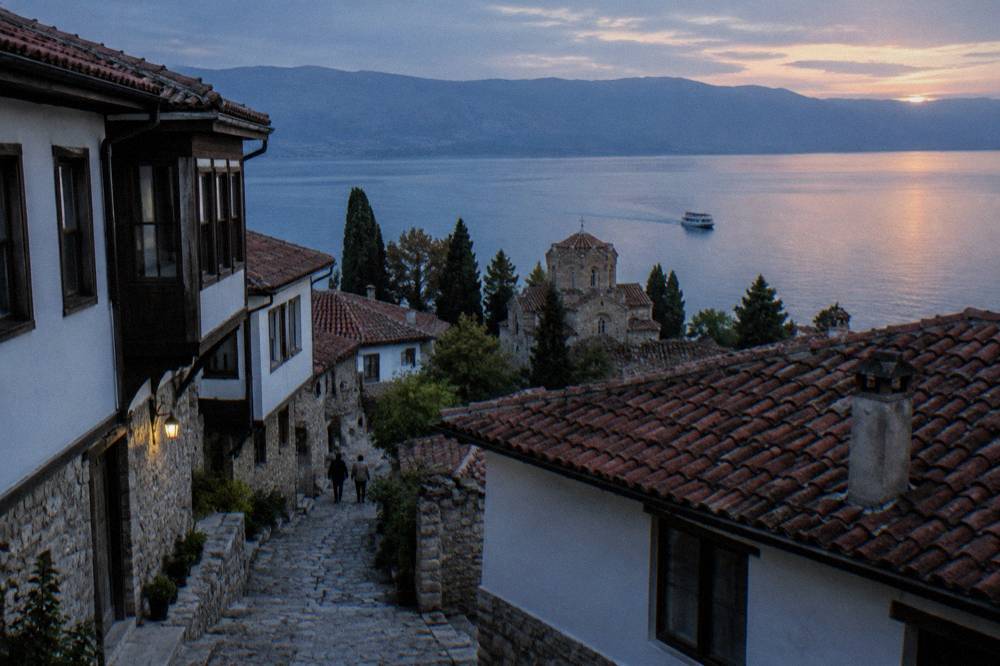 A small boat crossing Lake Ohrid at sunset below the old town rooftops