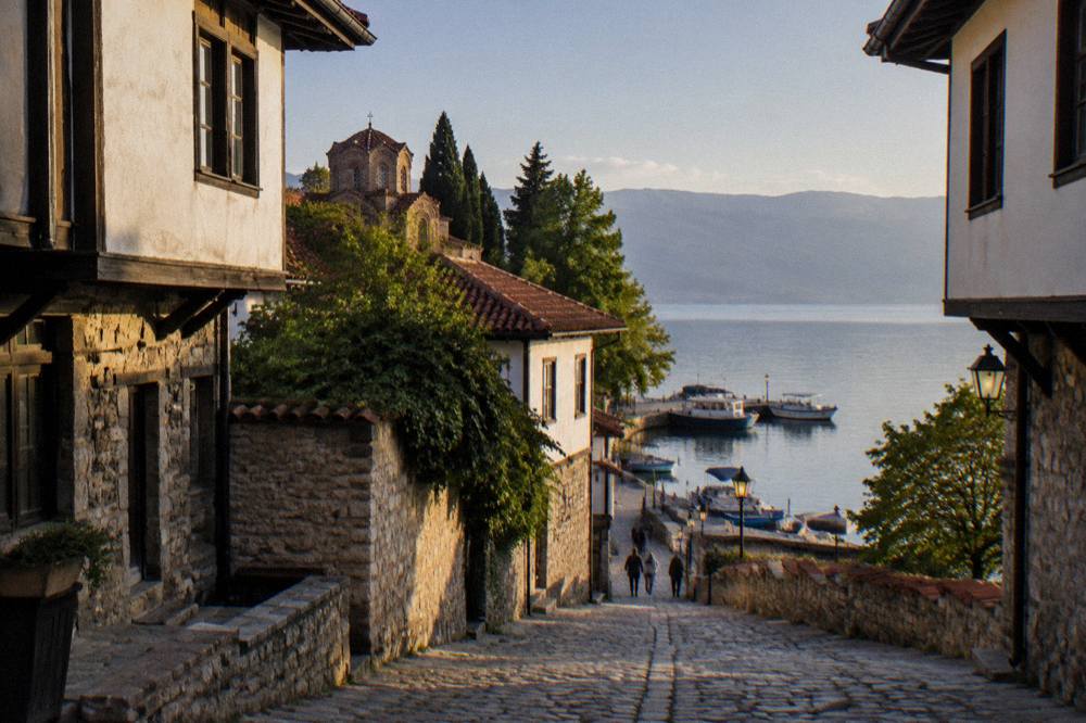 The Ohrid harbour at dusk with boats moored and lanterns lit along the quay