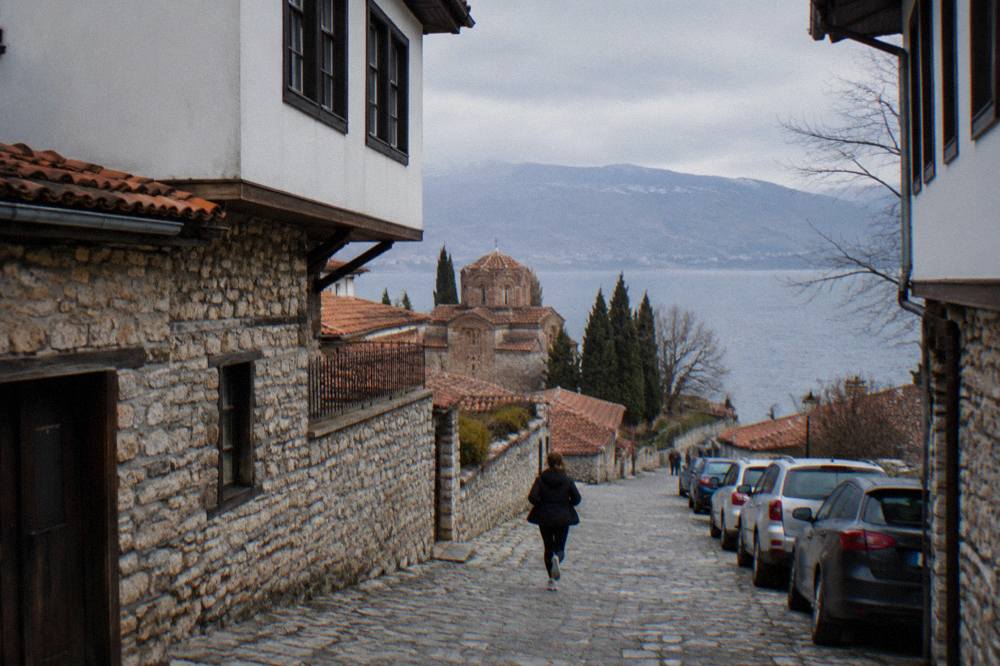 Parked cars along a street at the edge of Ohrid's old centre with the lake beyond