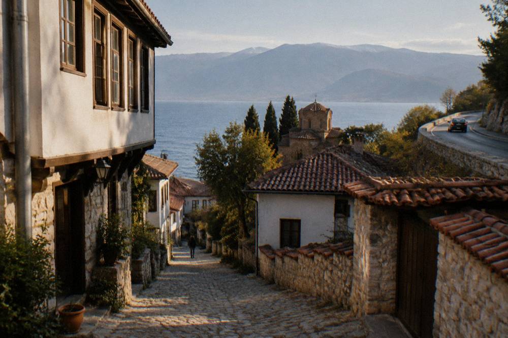 A car driving a curved road above Lake Ohrid toward the town