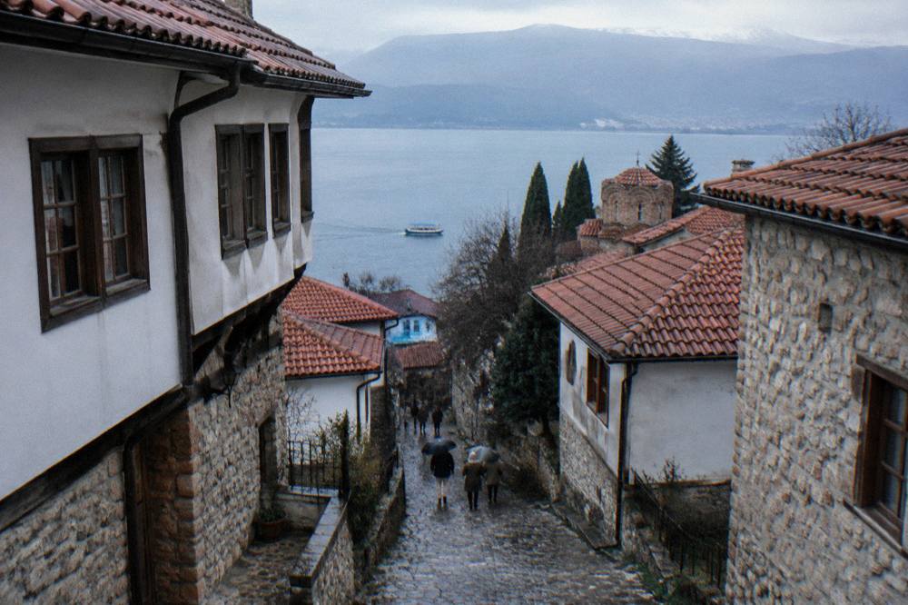 A boat on blue water near the Ohrid lakeshore with the town behind
