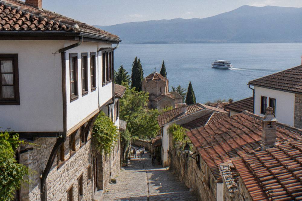 A passenger boat departing Ohrid harbour across calm blue water in early evening