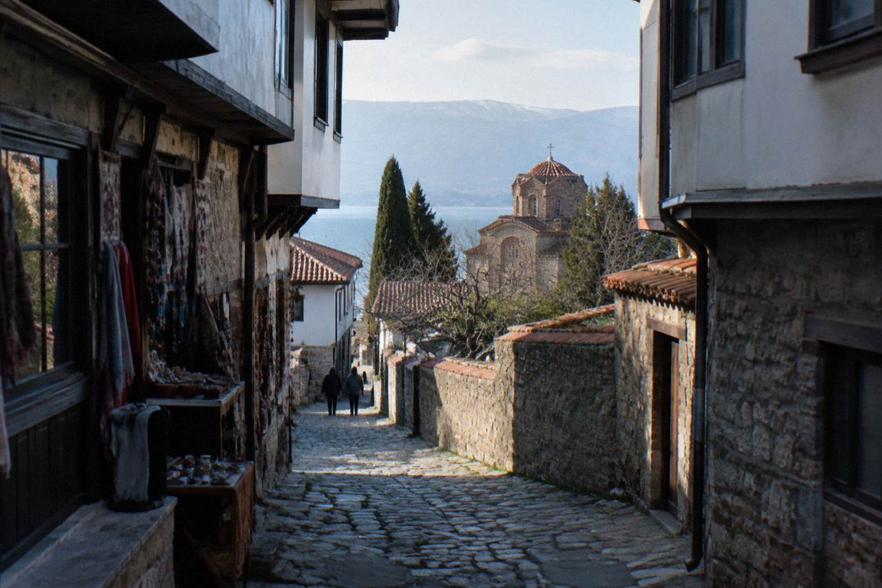 A narrow shopping street in Ohrid's old town with small storefronts and stone walls