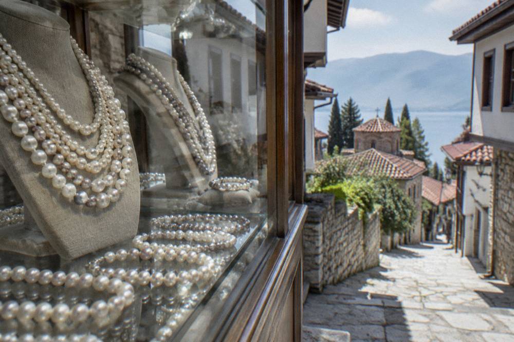 Close-up of Ohrid pearl necklaces displayed in a glass case in a workshop shop