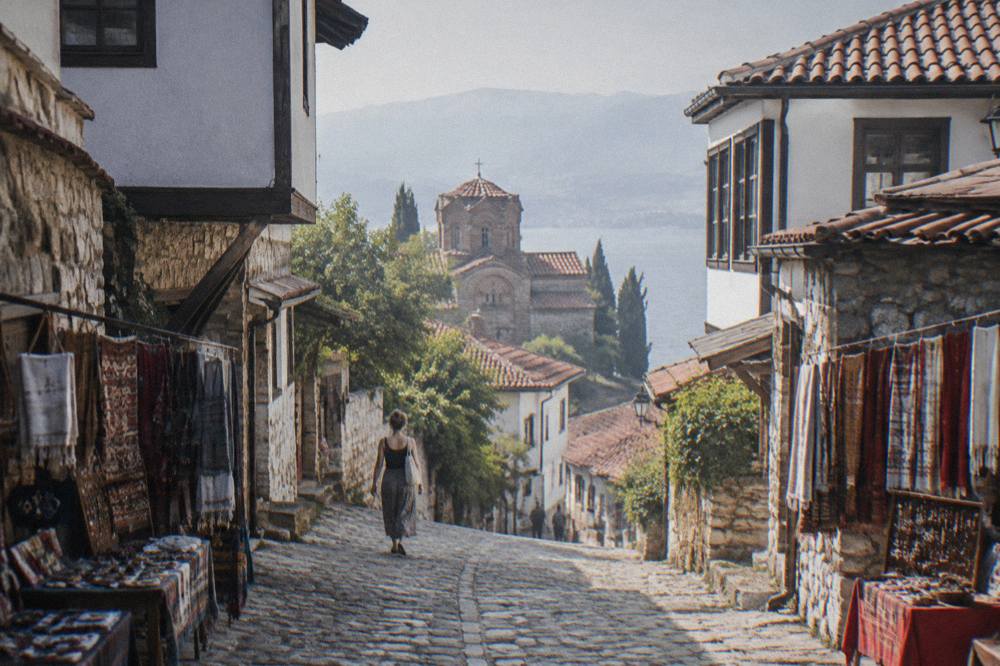 Market stalls with textiles and crafts lined up along a street in Ohrid