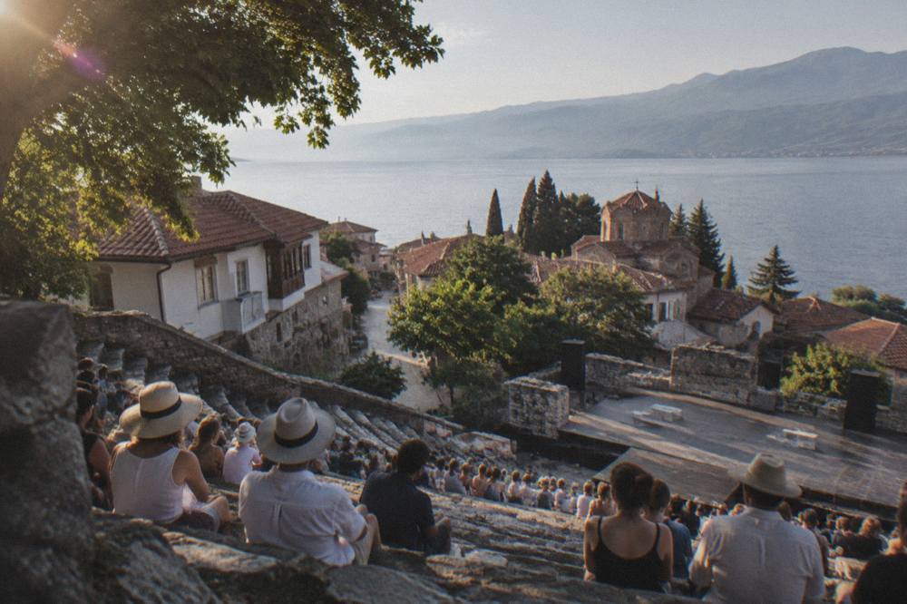 Audience seating on stone steps of an ancient hillside theatre before an evening performance