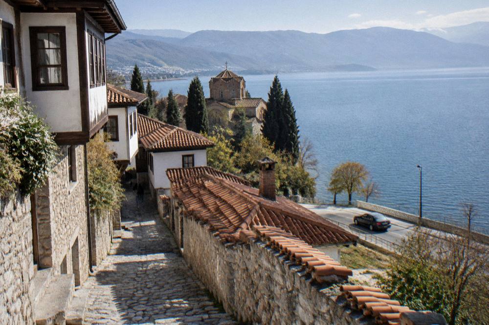 A taxi driving along a lakeside road at dusk with Lake Ohrid on one side