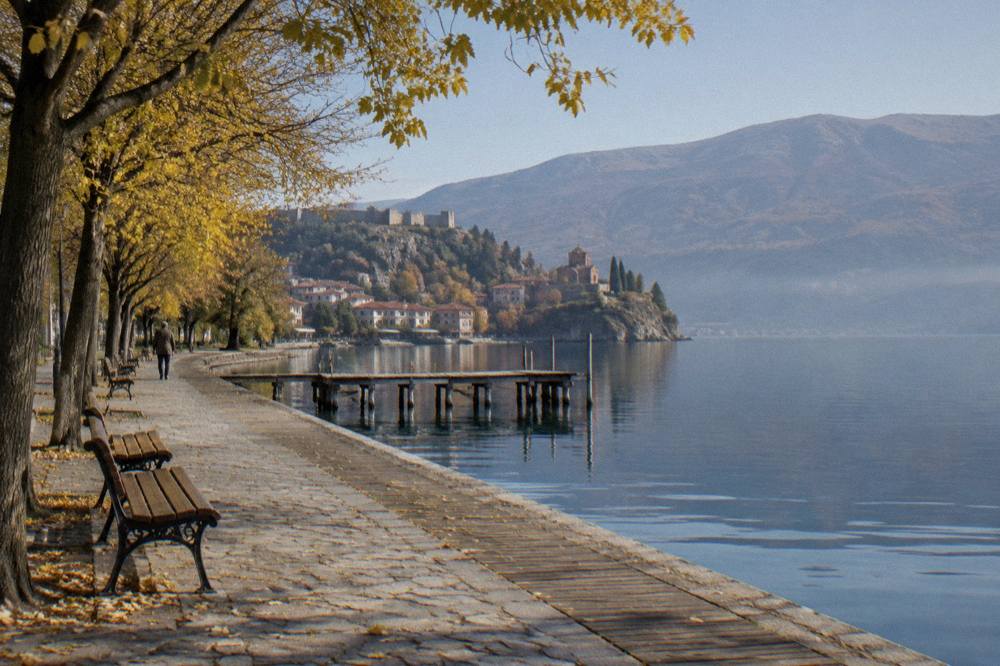 A quiet lakeside promenade in Ohrid in late autumn with empty benches along the water