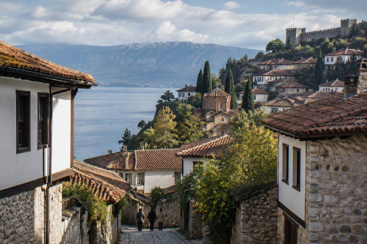 The old town of Ohrid seen from the water, with stone houses rising up the hillside toward the fortress walls