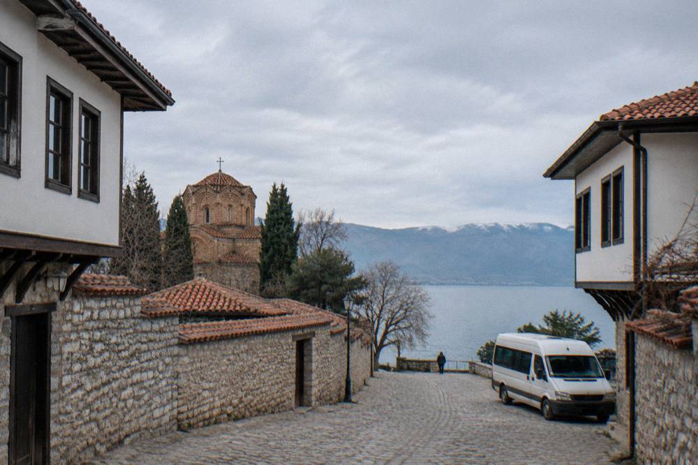 A minibus parked on a street beside a lake shore in the morning