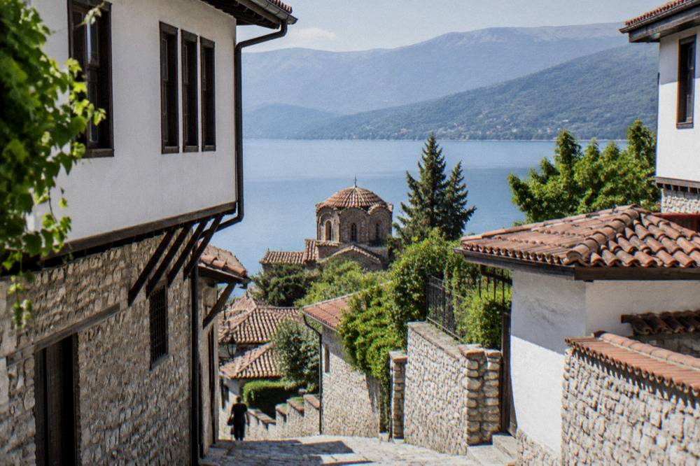 Lake Ohrid at midday with clear water and wooded hills on the far shore