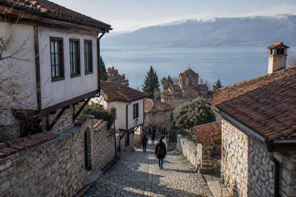 A lakeside old town with red roofs and a stone church above clear water