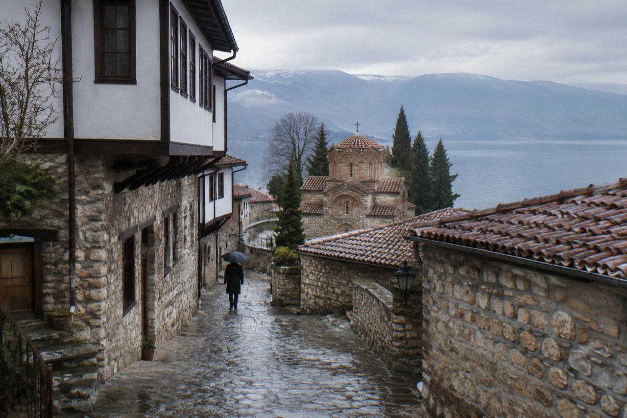 Stone houses and church towers of Ohrid old town rising above the blue water of Lake Ohrid