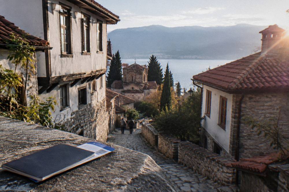 A passport and boarding pass resting on a map of the Balkans at a sunny table