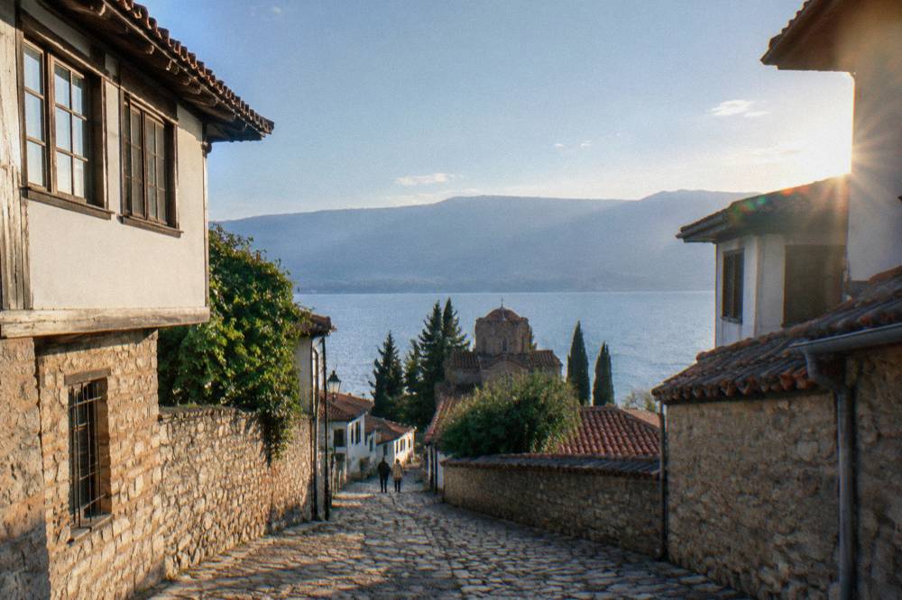 Clear water of Lake Ohrid along a pebble shore with hills behind