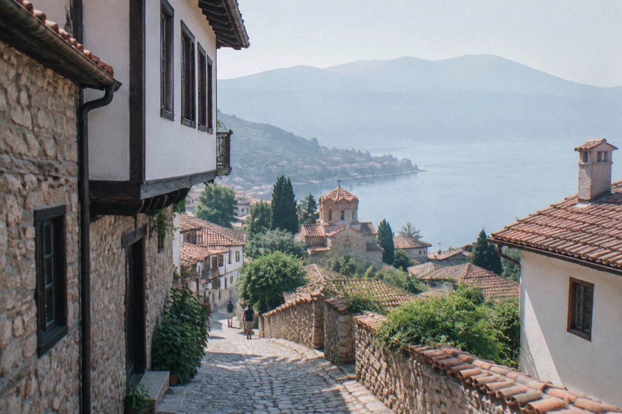 Red-roofed old town houses of Ohrid rising from the shore of a blue mountain lake toward a hilltop fortress