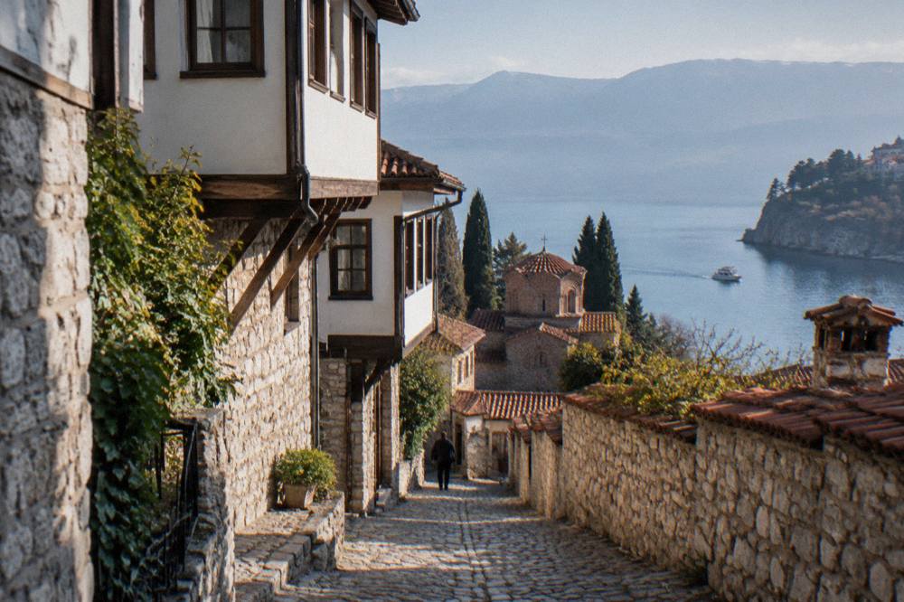 A small boat cruising along the shore of Lake Ohrid near cliffs