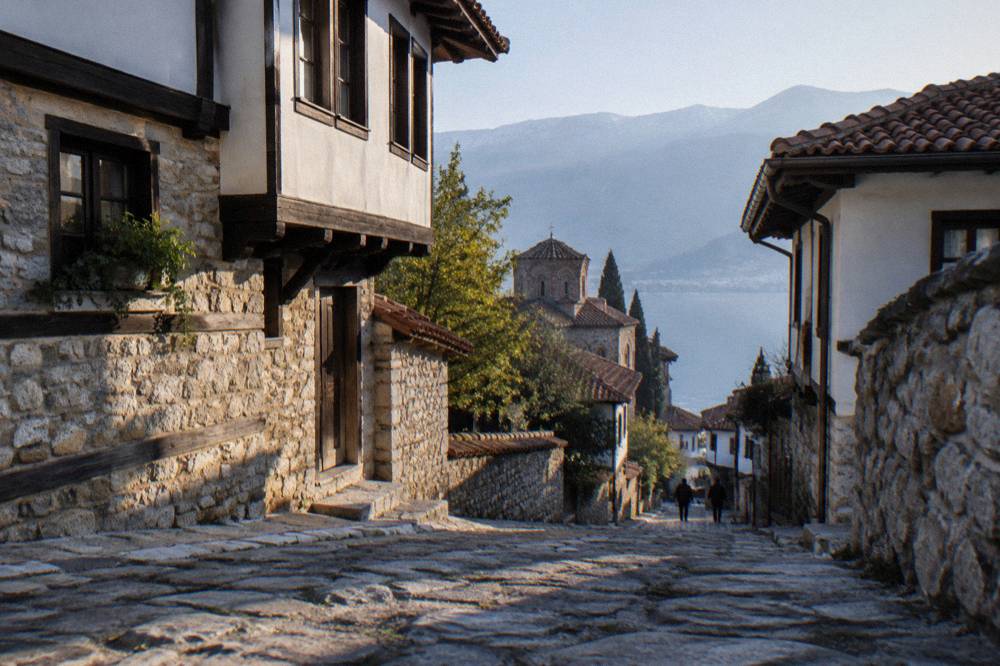 A road running along the shore of a lake with a small town ahead