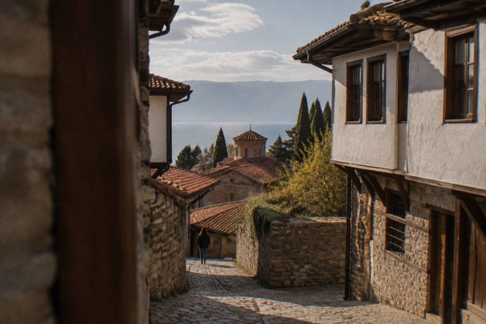 Red-tiled roofs of Ohrid old town with Lake Ohrid and mountains behind under scattered clouds