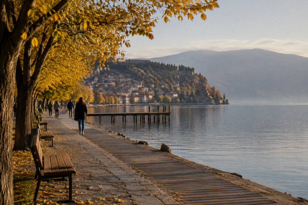 Autumn trees along the Ohrid lakeside promenade with the lake calm behind